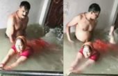 বন্যার পানিতে ঘরেই স্ত্রীকে সাঁতার শেখাচ্ছেন স্বামী ! (ভিডিও)
